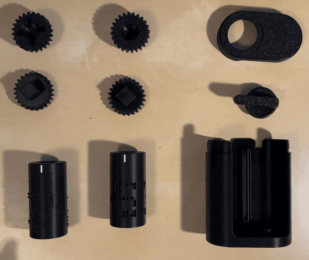 The 3D-printed embosser components: the generated roller, the frame, and the handle that press braille into a standard card