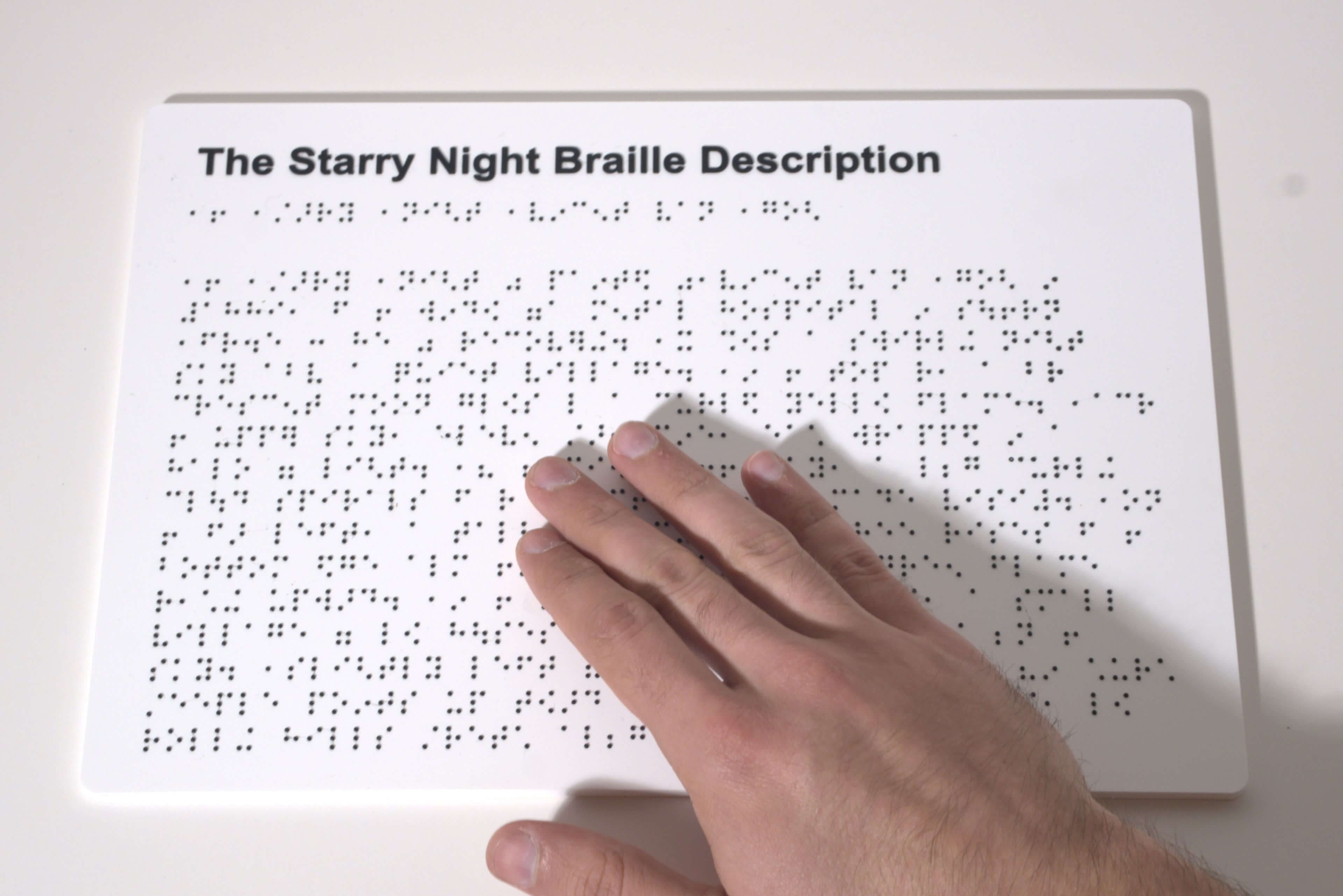 Hand reading a braille description panel for Starry Night